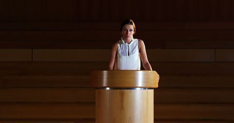 Confident Woman Behind Podium in Wooden Paneled Room