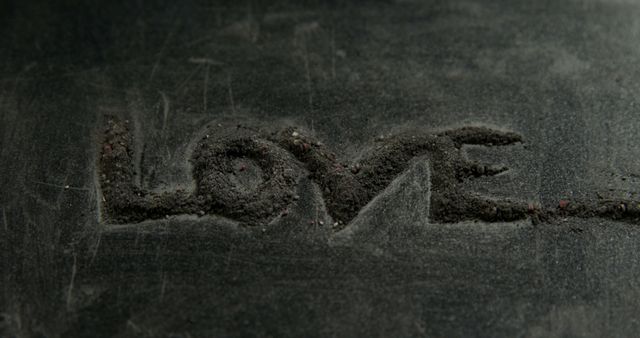 Word 'LOVE' is etched into a dark, textured surface, with copy space. Its simplicity and the universal message of love make it a powerful and evocative image.