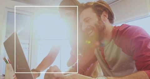 Happy team collaboration with laptop in bright office