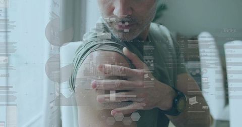 Mature man touching upper arm with digital health data overlay, telehealth monitoring