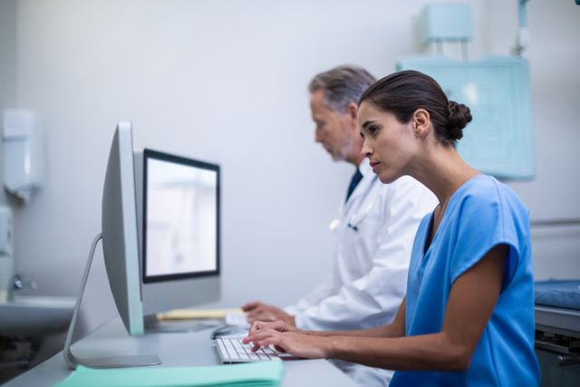 Doctor and nurse working together on a computer in a hospital environment. Ideal for use in healthcare, medical technology, and teamwork-related content. Can be used to illustrate collaboration in medical settings, healthcare technology, and professional teamwork.