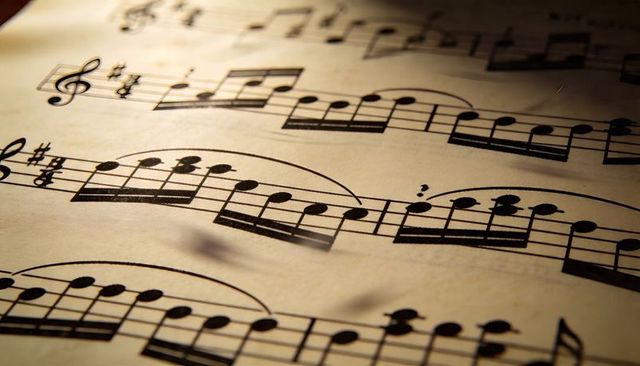 Vintage treble clef sheet music under warm angled light showing musical notation texture
