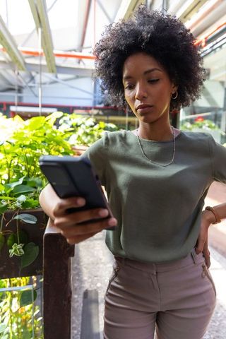 Woman using smartphone inside modern greenhouse