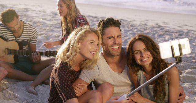 Young Friends Taking Selfie on Beach with Guitar Player in Background - Download Free Stock Images Pikwizard.com