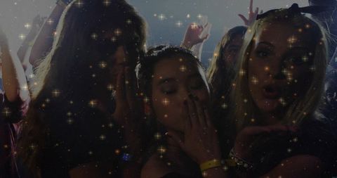 Three partygoers blowing kisses at nightclub with sparkling lights and backlight