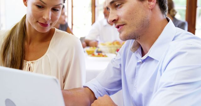 Couple using laptop in restaurant