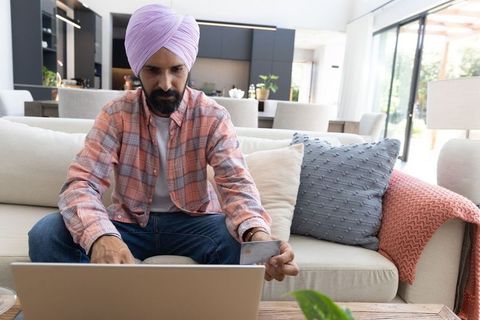 Indian man shopping online in modern living room interior