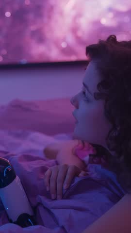 Child watching robot while lying in bed under nebula glow, waiting for reply
