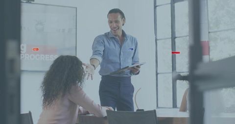 Team leader presenting with tablet and extending hand in bright modern conference room