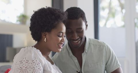 Friends Sharing Smartphone and Smiling Indoors