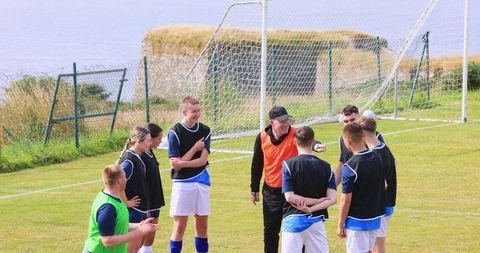 Teen Soccer Players Huddled with Coach Discussing Strategy by Waterfront