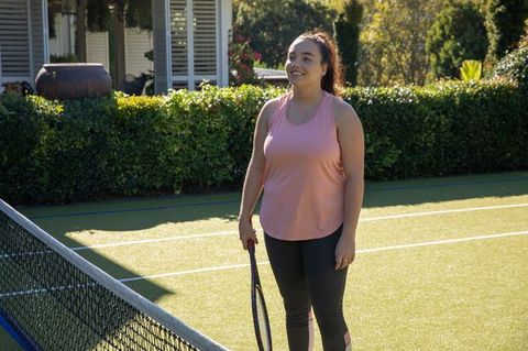Female tennis player holding racket on outdoor turf court