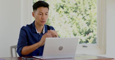Man Working Remotely at Home with Laptop by Sunlit Window