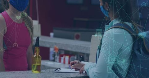 Woman wearing face mask writing on clipboard during pandemic