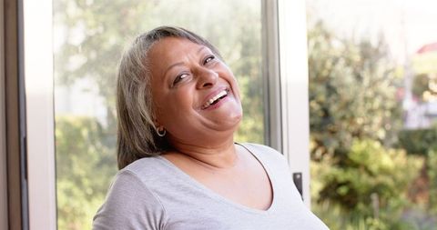 Joyful Senior Woman Smiling Near Sunlit Window