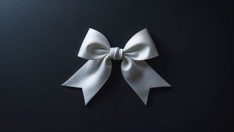 White ribbon bow on dark matte surface conveying elegance