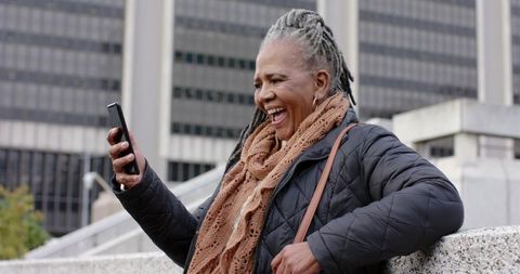 Senior African American Woman Laughing During Video Call on Smartphone in Urban Plaza
