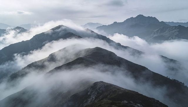Fog-Flowing Remote Alpine Ridge at Dawn with Layered Peaks, Jagged Summits and Moody Mist