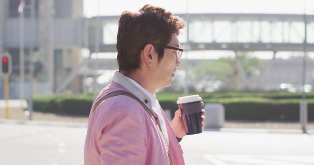 Asian man drinking coffee and using smartphone while walking on the street. business and lifestyle concept