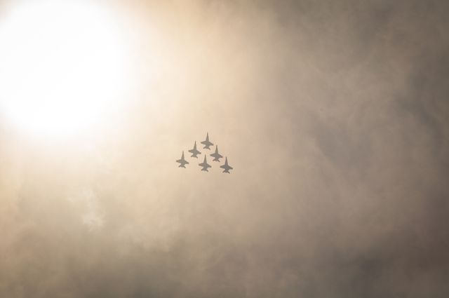Several aircraft flying in a tight formation against a cloudy sky with sunlight filtering through. The image evokes themes of teamwork, precision, and strength. It is ideal for use in content relating to aviation, military, aerodynamics, or teamwork.