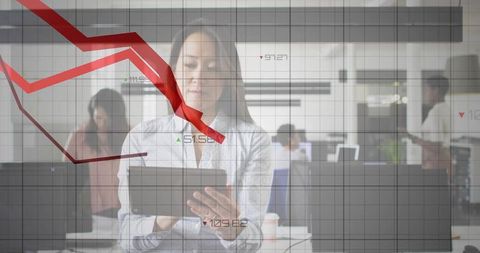 Businesswoman analyzing falling stock chart on tablet with team working in office