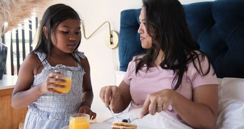 Mother and daughter enjoying breakfast together in bedroom