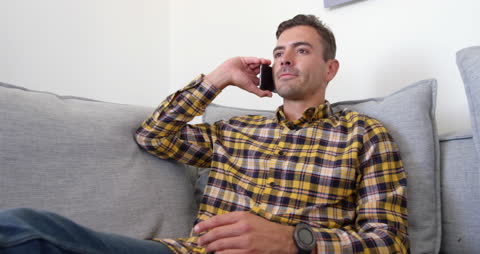 Young Man in Living Room Taking Phone Call Relaxing
