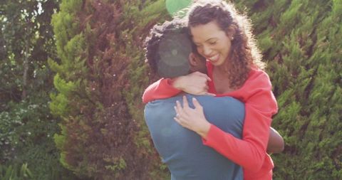Joyful embrace of engaged couple in sunlit garden