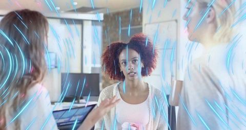 Listening woman holding travel mug during intense team discussion in open workspace