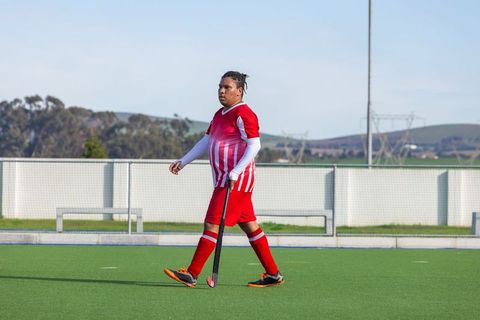African American Male Athlete Training on Field with Hockey Stick
