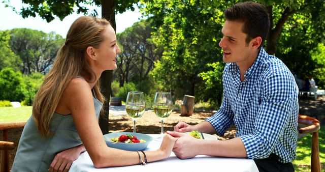A young Caucasian couple enjoys a romantic outdoor lunch, with copy space. Their intimate conversation and relaxed demeanor suggest a comfortable and affectionate relationship.