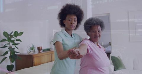 Young Woman Assisting Senior during Arm Rehabilitation Exercise