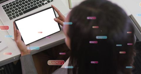 Businesswoman holding tablet over laptop with floating data tags, hud interface