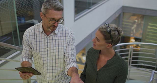 Man and woman discussing work on staircase in modern office - Download Free Stock Images Pikwizard.com