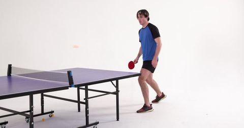 Athlete Engaged in Energetic Table Tennis Play in Studio Setting