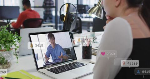 Korean presenter gesturing on laptop during virtual meeting with social engagement icons