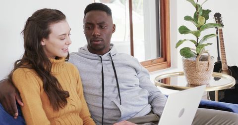 Happy Interracial Couple Using Laptop in Modern Living Room