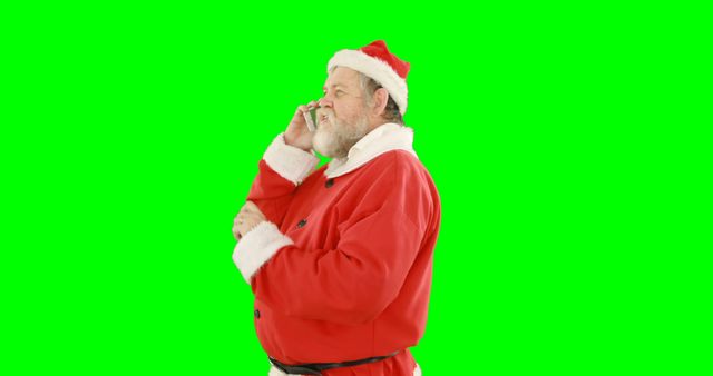 Santa Claus is using his mobile phone with a vibrant green screen background. This could be perfect for holiday-themed marketing materials, social media posts, or Christmas party invitations and promotional content where you could overlay your own background.