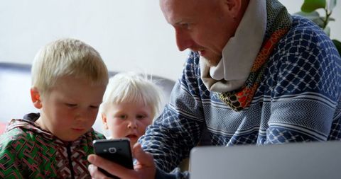 Father and sons enjoying mobile technology at home
