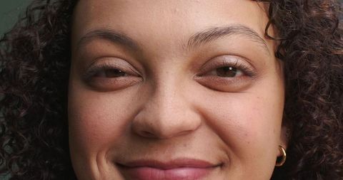 African woman in 20s smiling close-up portrait with curly hair and gold hoop earring