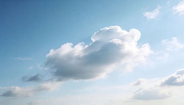 Sunlit cumulus cloud drifting over tranquil blue sky with rim light and wisps