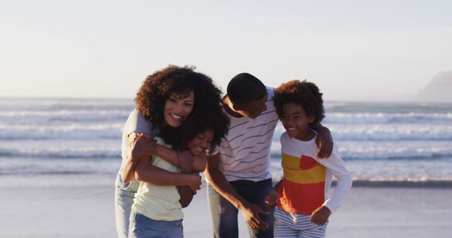 Happy family spending quality time together at the beach, hugging and smiling. Use this image for promoting family activities, beach vacations, or advertisements showing family togetherness and bonding.