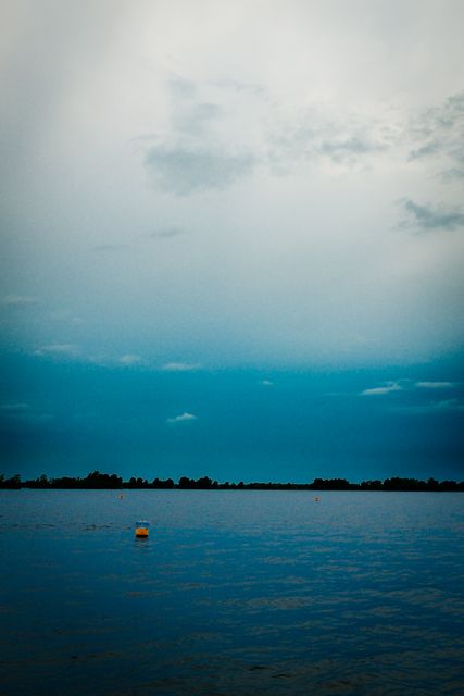 Tranquil Blue Lake with Buoy Under Cloudy Sky - Download Free Stock Photos Pikwizard.com