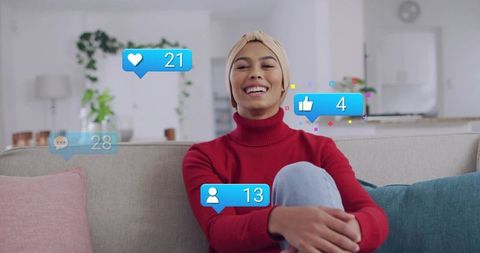 Smiling woman wearing headscarf relaxing on sofa with social media engagement overlays