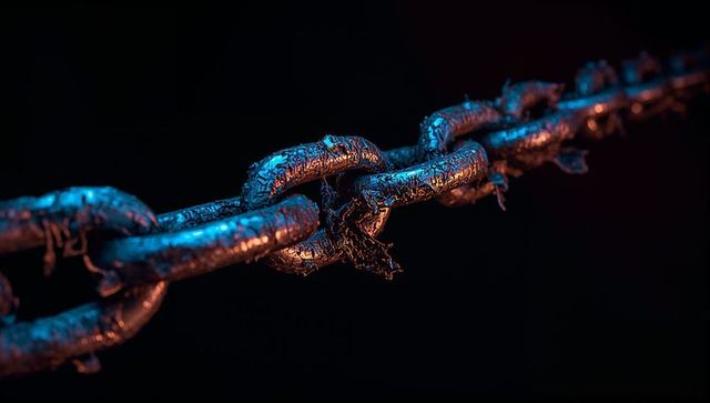 Corroded chain breaking under strain with neon rim lighting, macro industrial detail