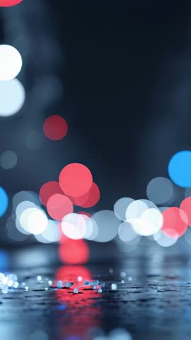 Vertical video capturing wet asphalt reflecting traffic bokeh and moody urban nightscape