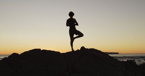 Silhouette of Man Practicing Yoga at Sunset on Rock by Sea - Download Free Stock Images Pikwizard.com