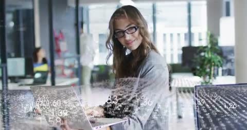 Female data analyst typing and reviewing live data visualization overlay in open-plan office