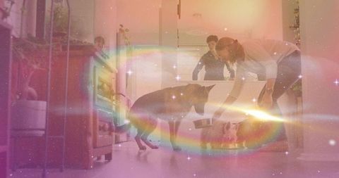 Bending woman placing metal bowl beside shepherd dog in dreamy kitchen with rainbow light