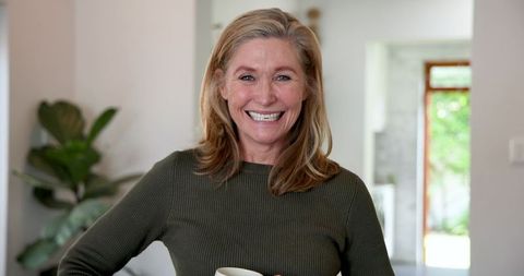 Happy Middle-aged Woman Relaxing at Home with Tea Mug